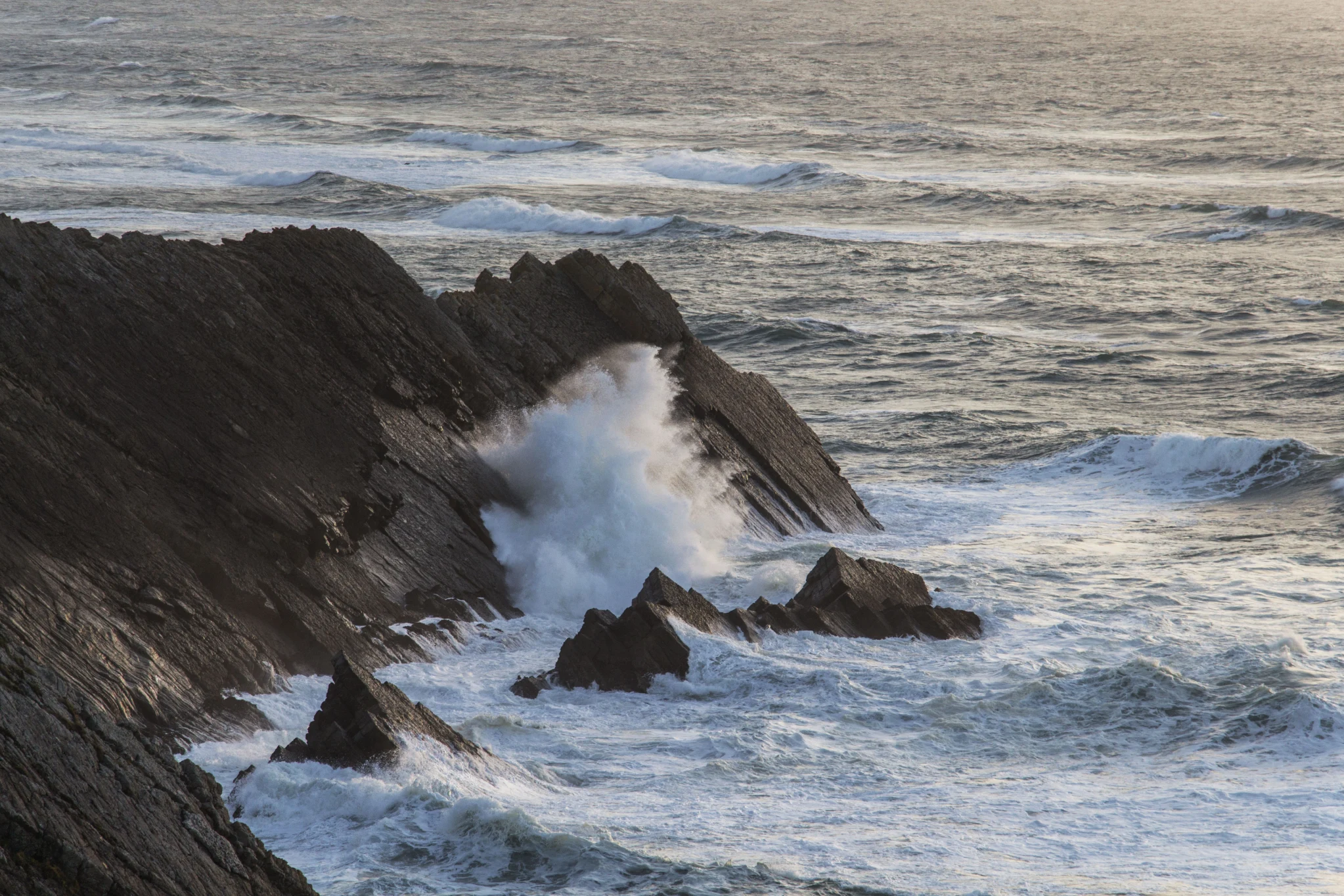 Puissance de la mer Bretonne, l'eau percute le rocher noir, vagues visibles durant le trek de la presqu'ile de crozon