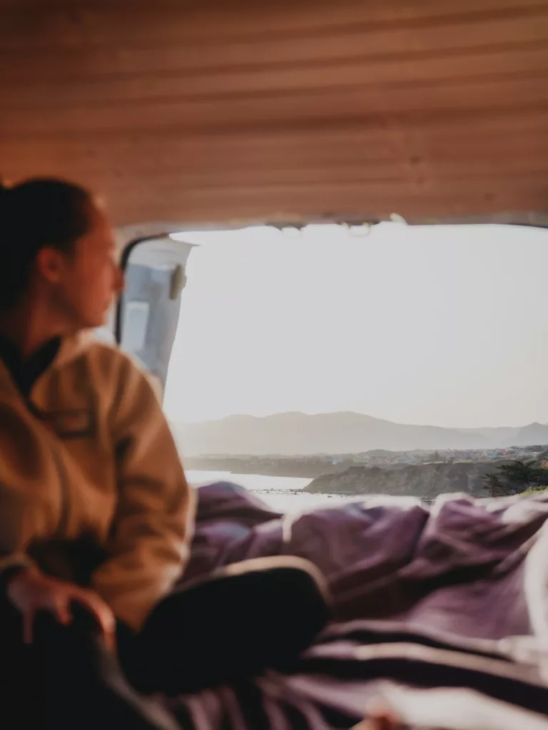 Femme dans un van qui admire la vue vers les paysages de la Sardaigne.