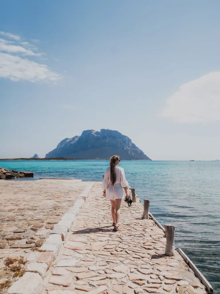 Femme marchant sur un quai au bord de la mer en Sardaigne (nord-est).