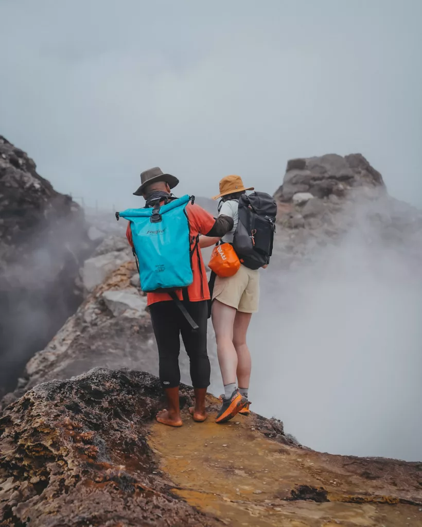Randonneuse face au cratère de la Soufrière, entre vapeur de soufre et paysage volcanique.
