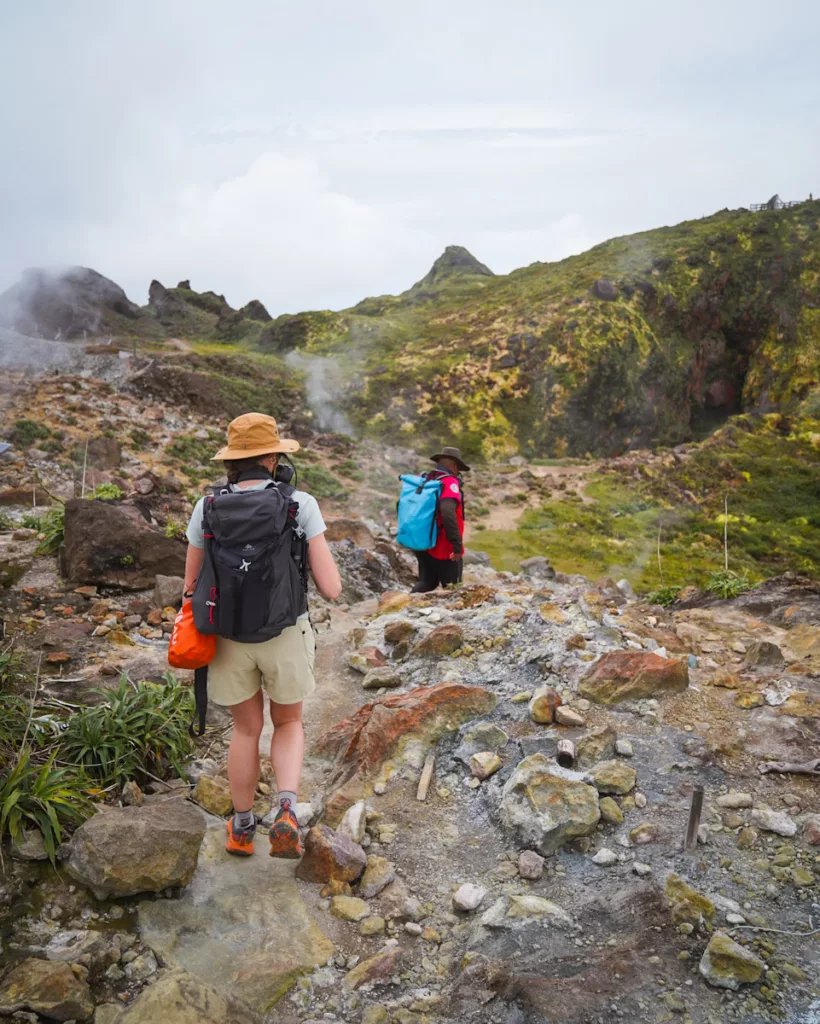 Randonneuse accompagnée d’un guide près des fumerolles de la Soufrière en Guadeloupe.

