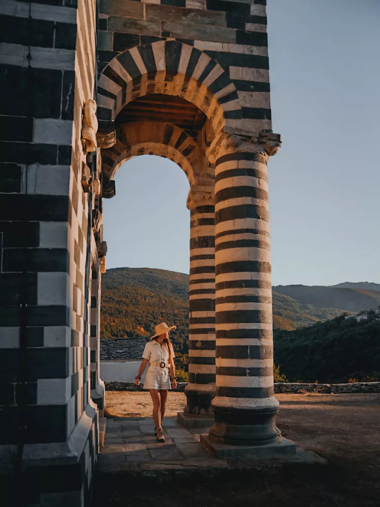 Eglise San Michele de Murato au coucher du soleil, église polychrome en serpentine verte et calcaire. Jeune femme qui marche devant l'ntrée de l'église.