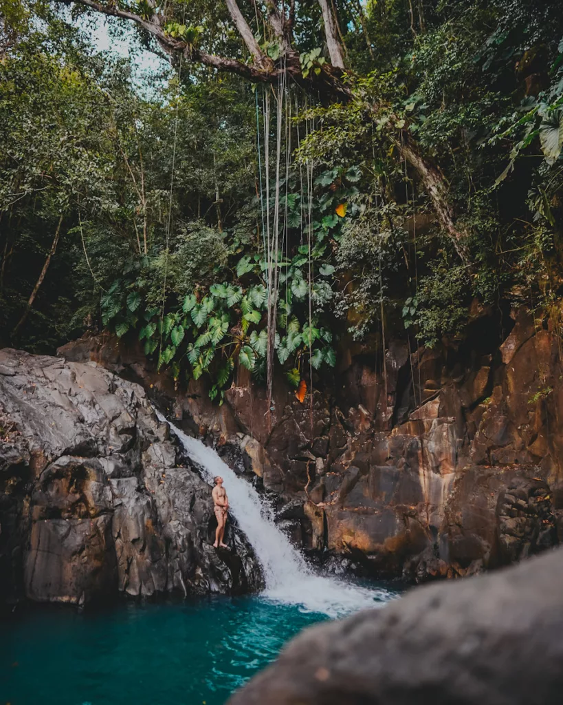 Randonneur au pied du Saut d’Acomat, cascade emblématique de Guadeloupe.