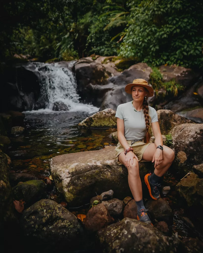 Randonneuse faisant une pause au bord d’une rivière tropicale sur le sentier des chutes du Carbet, en Guadeloupe.


