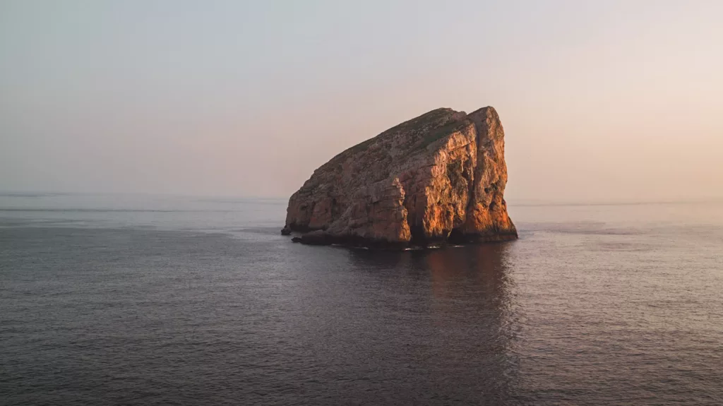 Rocher dans la mer à Capo Caccia, site d'escalade pour grimper en Sardaigne au coucher du soleil.
