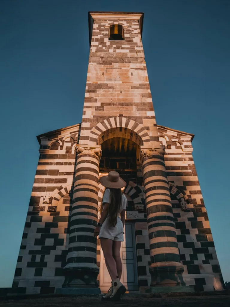 Jeune femme avec un chapeau de soleil devant la façade de l'Eglise San Michele de Murato en haute-Corse dans la région du Nebbiu.