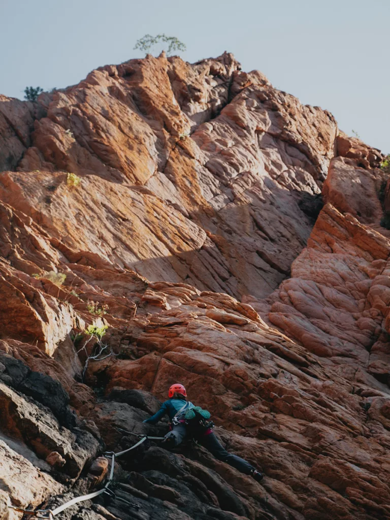 Grimpeuse sur la falaise de granite orange de l'Ambata di Melu, grande voie d'escalade en Corse.