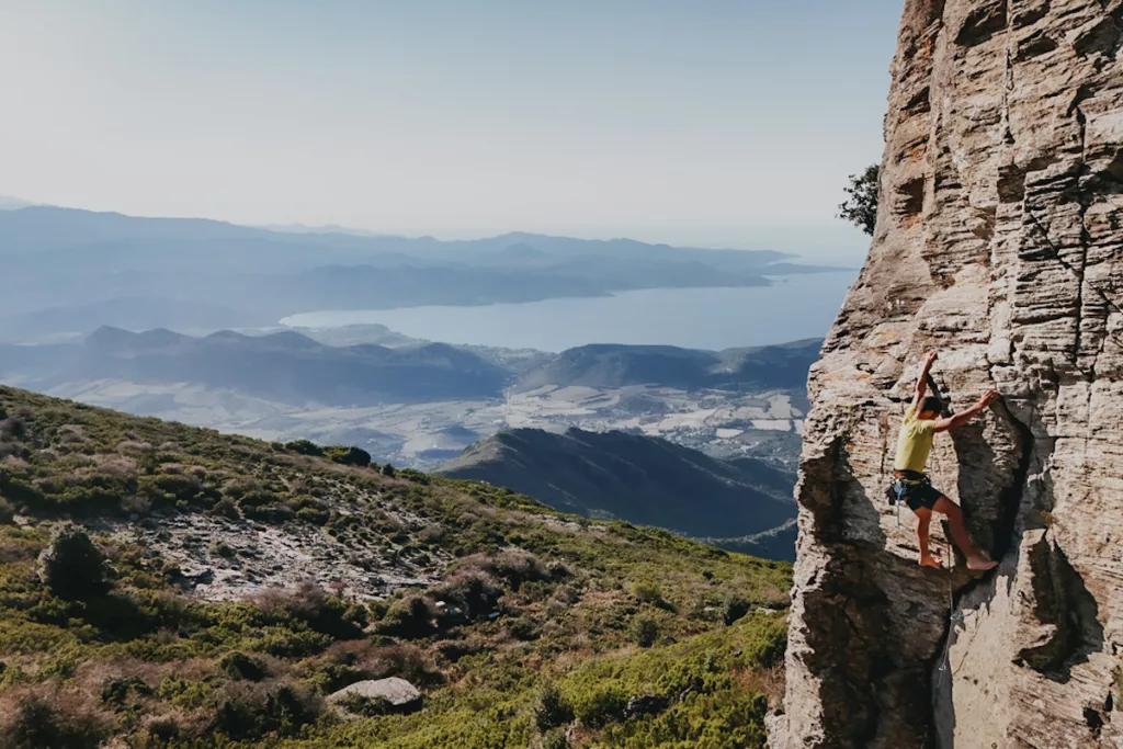 Grimpeur en Corse qui fait de l'escalade nu pied sur la falaise des Antennes proche de Bastia.