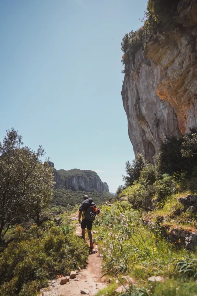 Grimpeur qui marche sur le sentier s'approche pour aller grimper à la falaise de Lecorci en Sardaigne.