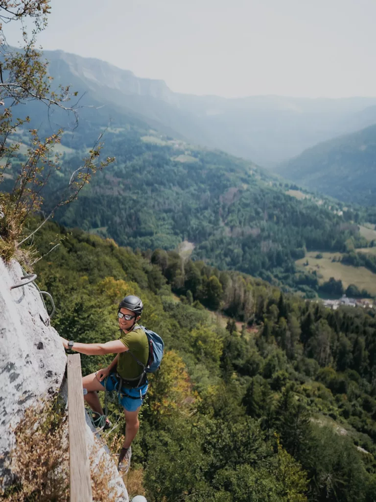Via Ferrata de la Roche Veyrand à Saint Pierre d'Entremont en Savoie, homme qui grimpe façe aux paysages de montagne.