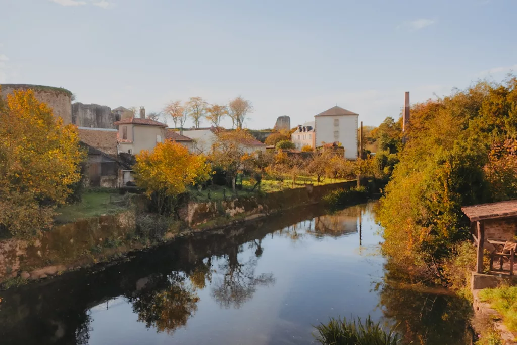 Vue de la rivière Thouet lors d’une visite de la cité médiévale de Parthenay, avec ses rives verdoyantes et le reflet des maisons anciennes dans l’eau.