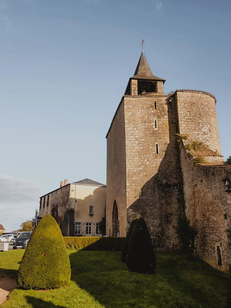 Vue de la Porte de l’Horloge depuis le jardin du tribunal lors d’une visite de la cité médiévale de Parthenay, avec la tour et le cadran de l’horloge se détachant sur le ciel.
