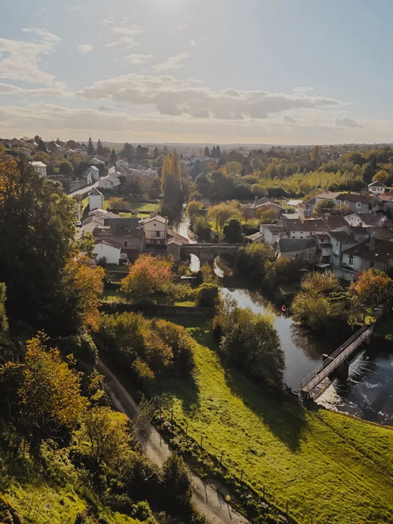 Vue panoramique sur la rivière Thouet depuis le jardin du tribunal lors d’une visite de la cité médiévale de Parthenay, avec les rives verdoyantes et les maisons anciennes en arrière-plan.