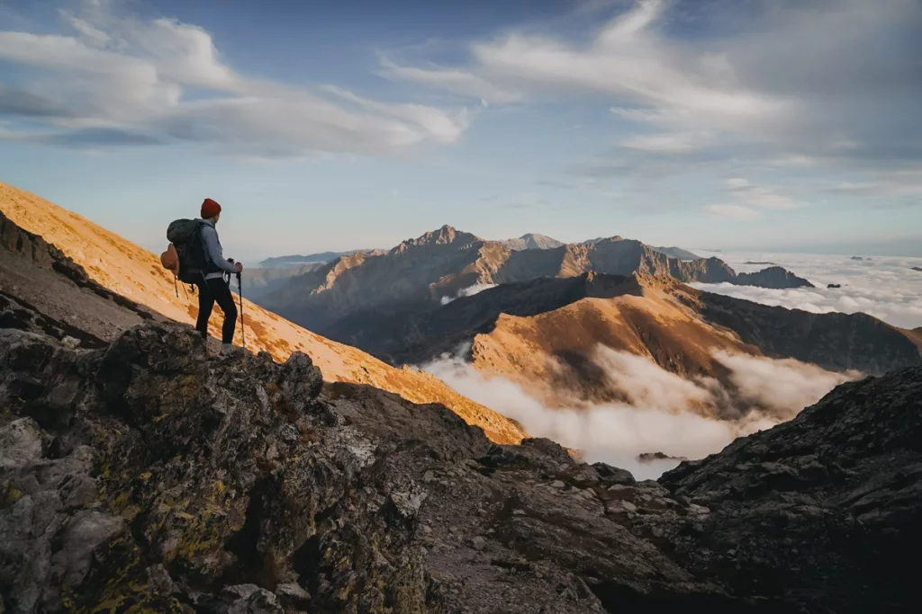 Randonneuse face aux paysages de la Corse prohe du refuge de Pietra Piana au coucher du soleil avec une mer de nuages.