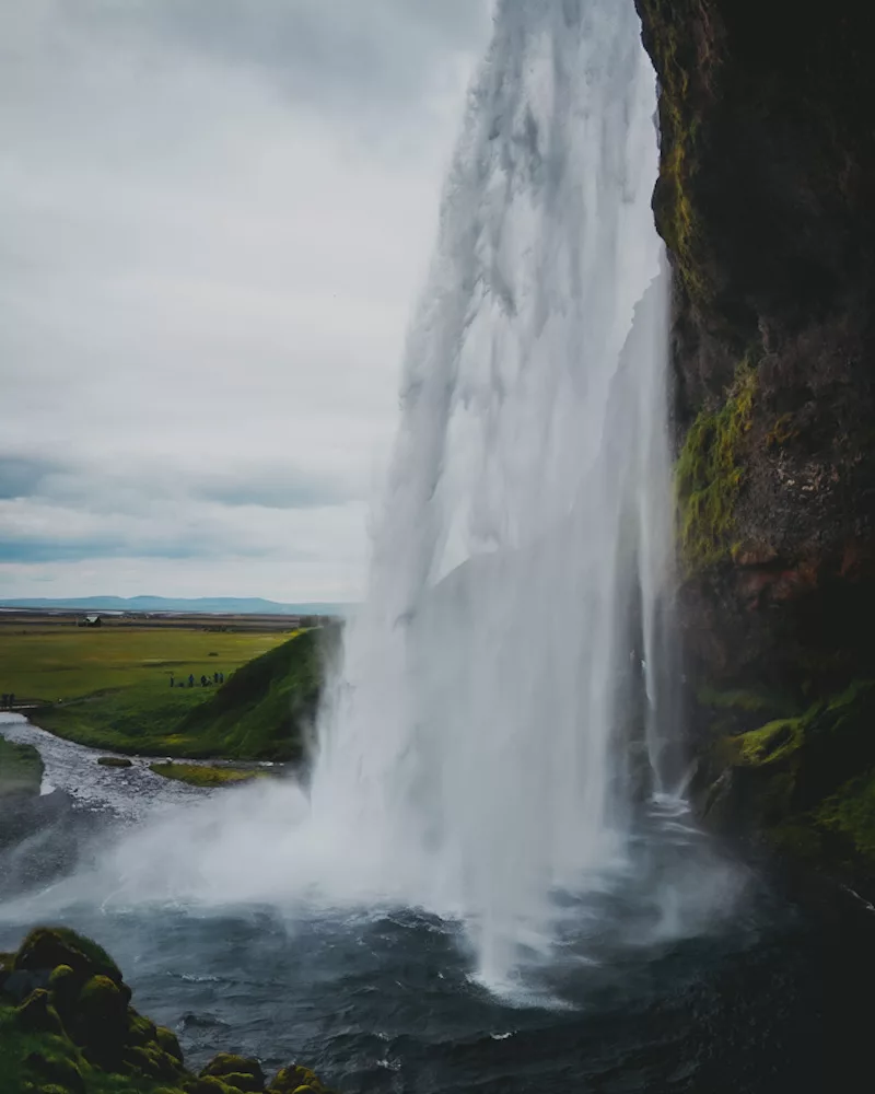 Randonnée à la cascade de Seljalandsfoss, vue de derrière la cascade par le petit sentier glissant et mouillé.