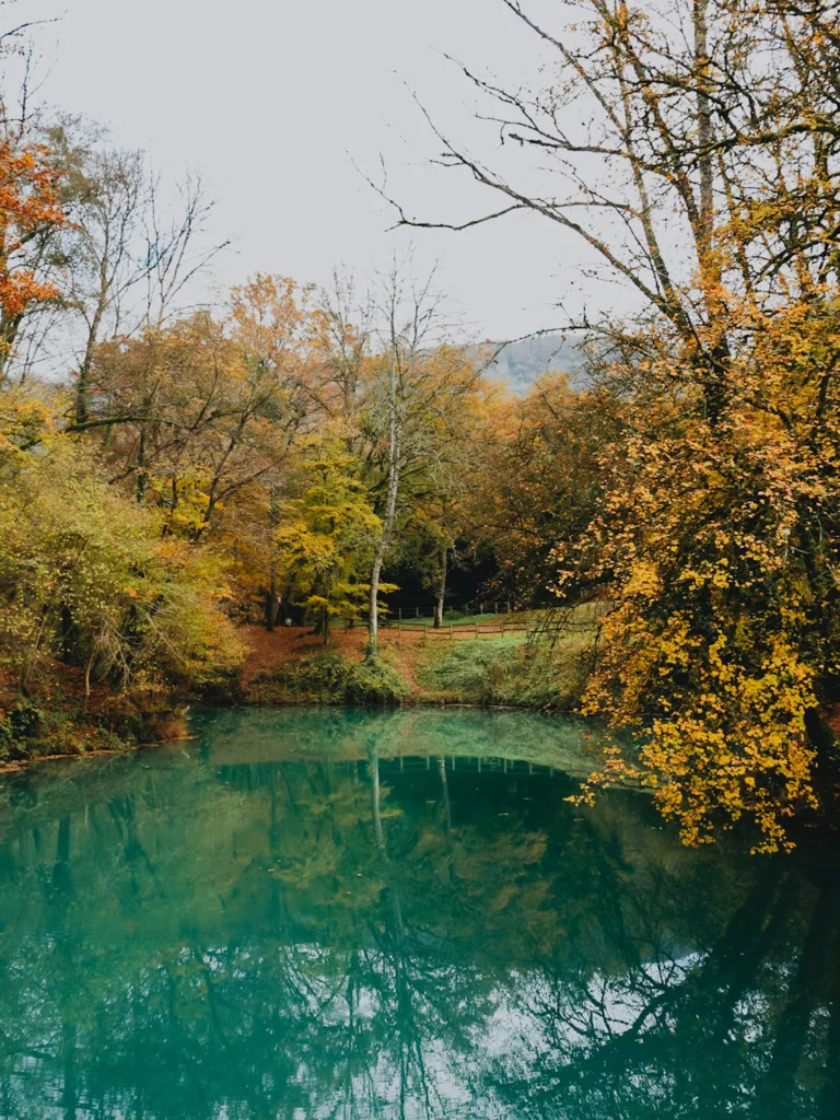 Lac bleu à Ambérieu en bugey, eau turquoise et arbres orangés à l'automne..