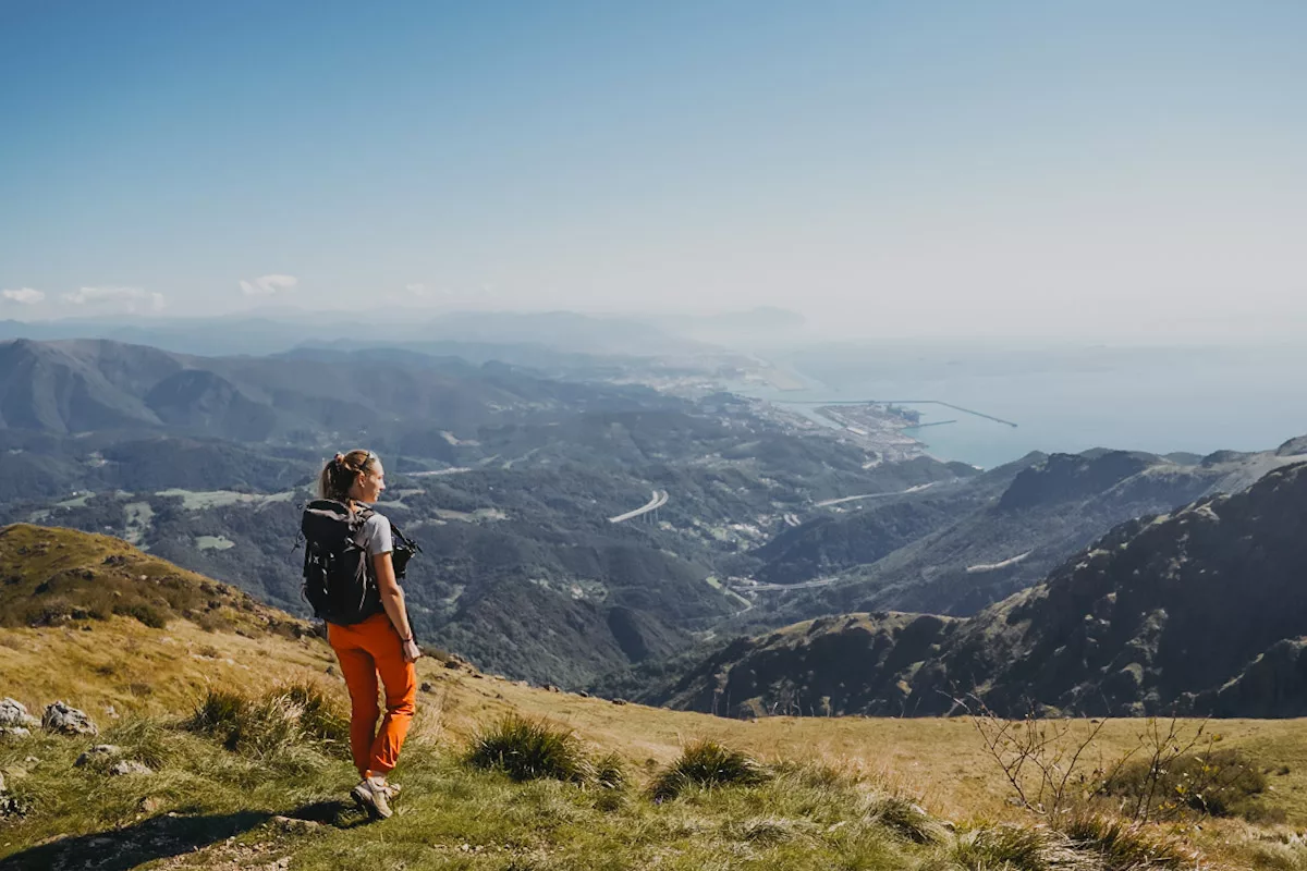 Randonneuse sur un sentier de randonnée au Monte Reixa proche de Gênes, vue sur la mer et sur le ville de Gênes randonnée en crêtes ensoleillée entre mer et montagne.