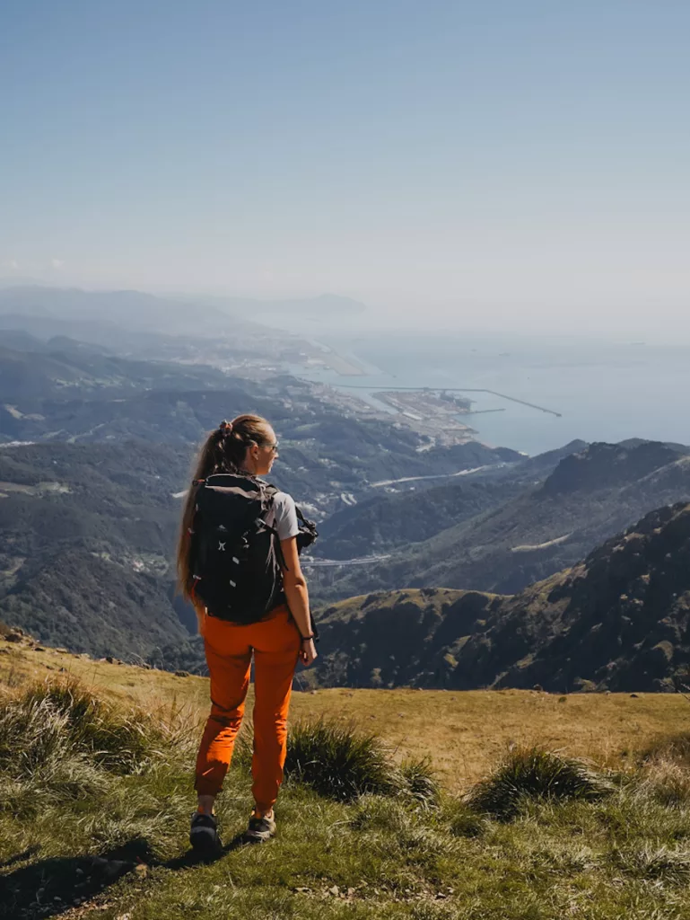 Randonneuse sur le Monte Reixa en Ligurie face à la vue sur la ville de Gênes et la mer Ligure.