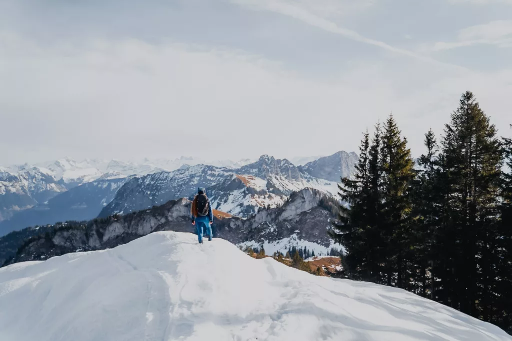 Randonnée en Suisse à Sörenberg depuis l'hôtel Rischli, randonneuse face aux paysages enneigés.