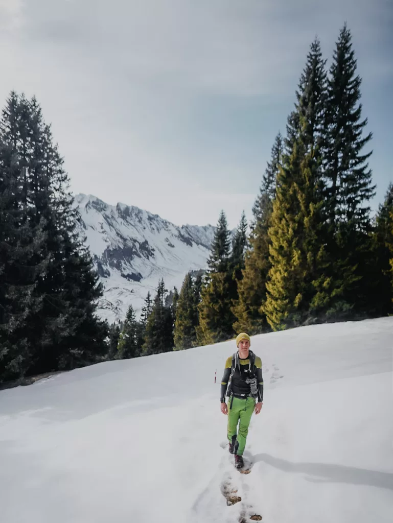 Randonnée en Suisse à Sörenberg depuis l'hôtel Rischli, randonneur dans la neige devant des sapins.