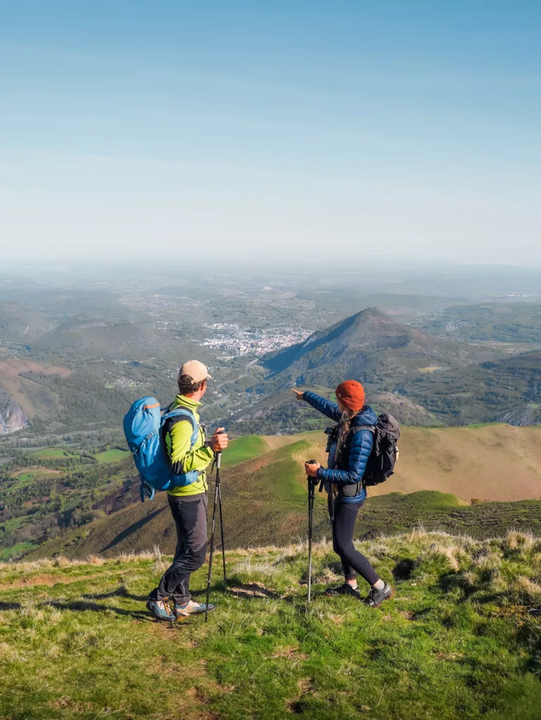 Vue sur Lourdes depuis le sentier de randonnées des Pyrénes. Deux randonneurs devant les paysages de Lourdes.