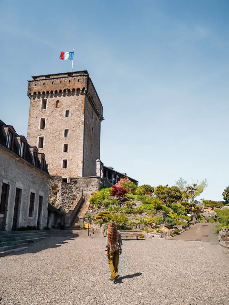 Visite du château fort médiéval de Lourdes : femme marchant devant la tour du château de Lourdes.
