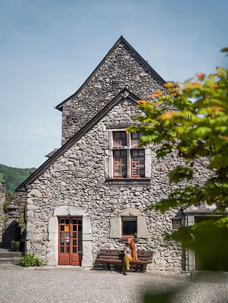 Visite du château fort médiéval de Lourdes : femme assise sur un banc devant le château de Lourdes.