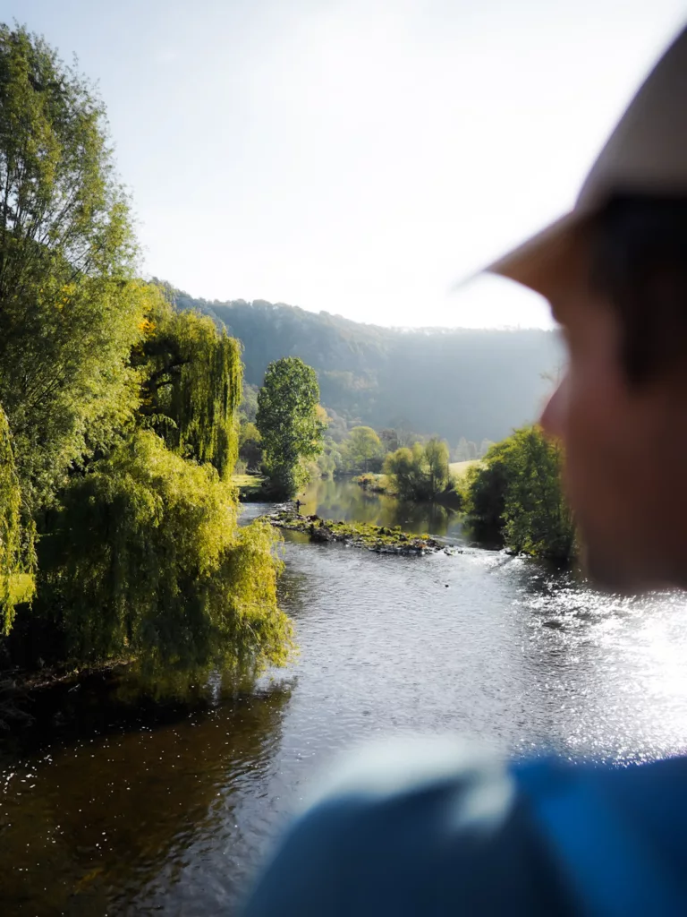 Randonnée en Normandie : le plus belle randonnée de Suisse Normande à Clécy. Randnneur qui regarde l'Oise avec une lumière du matin.