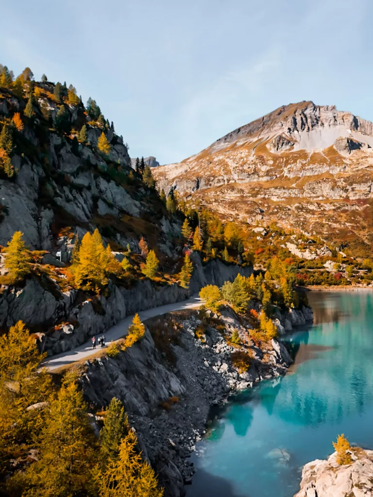 Le lac d'Emosson avec les couleurs d'automne : eau bleue et mélèzes orangées. Magnifiques paysages à découvrir en Suisse.